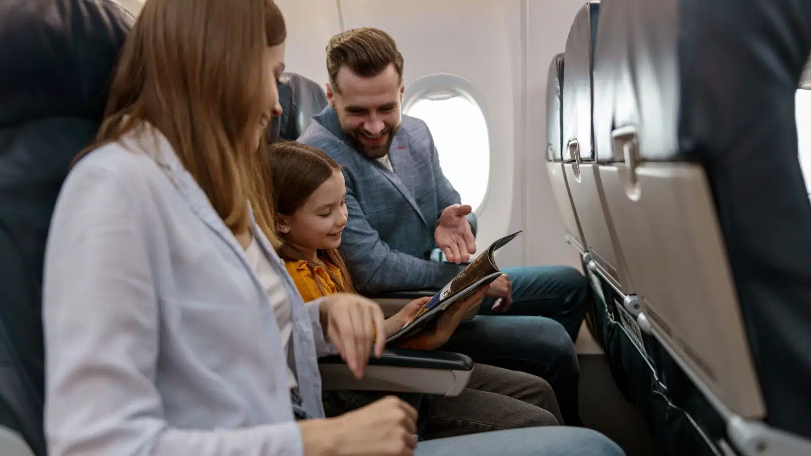 A happy family prepares to have a safe flight while seated in an airplane.