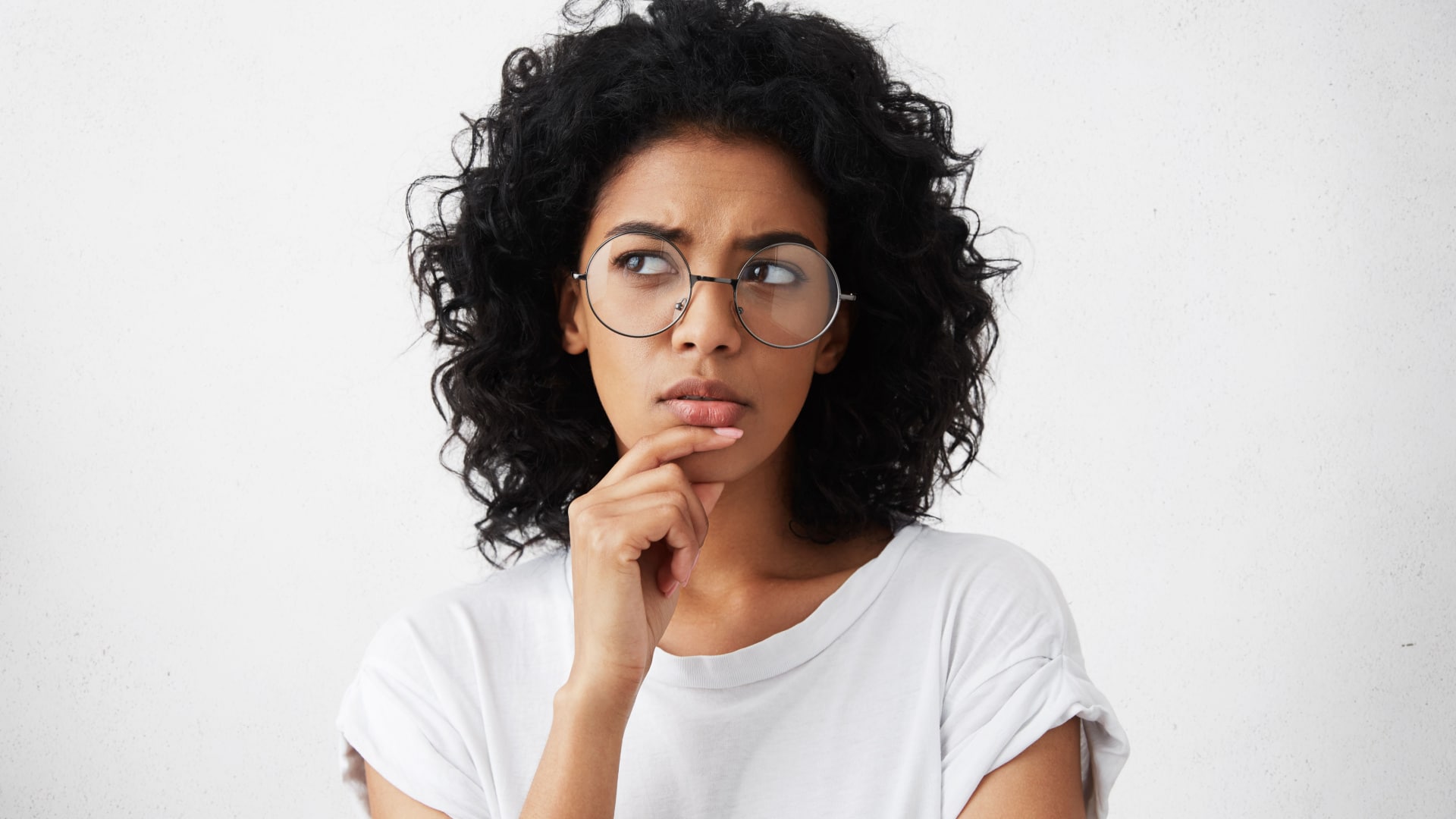 Woman with her hand on her chin with a thinking look on her face.