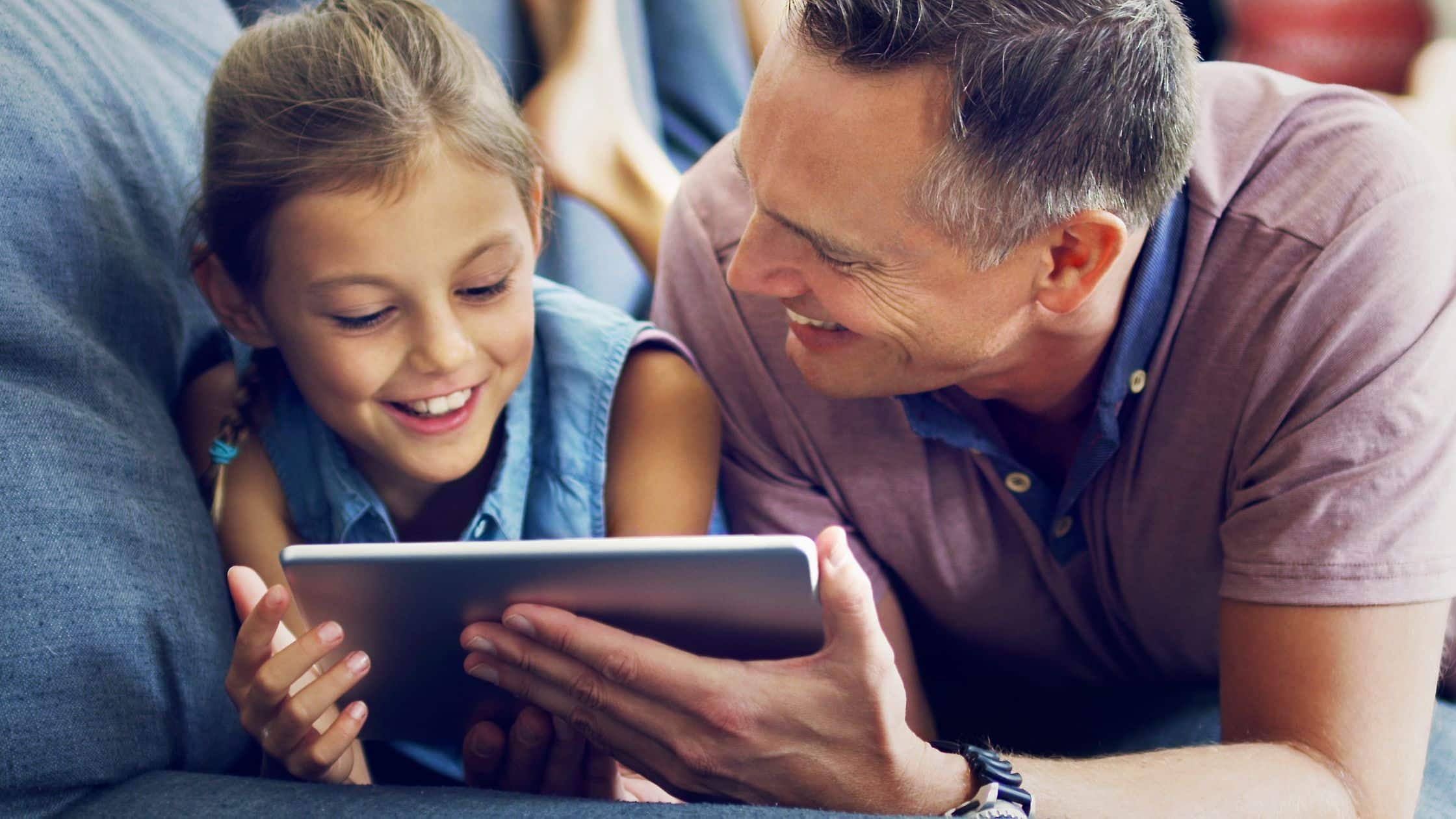 Father and daughter playing together on a tablet to represent Discord Safety