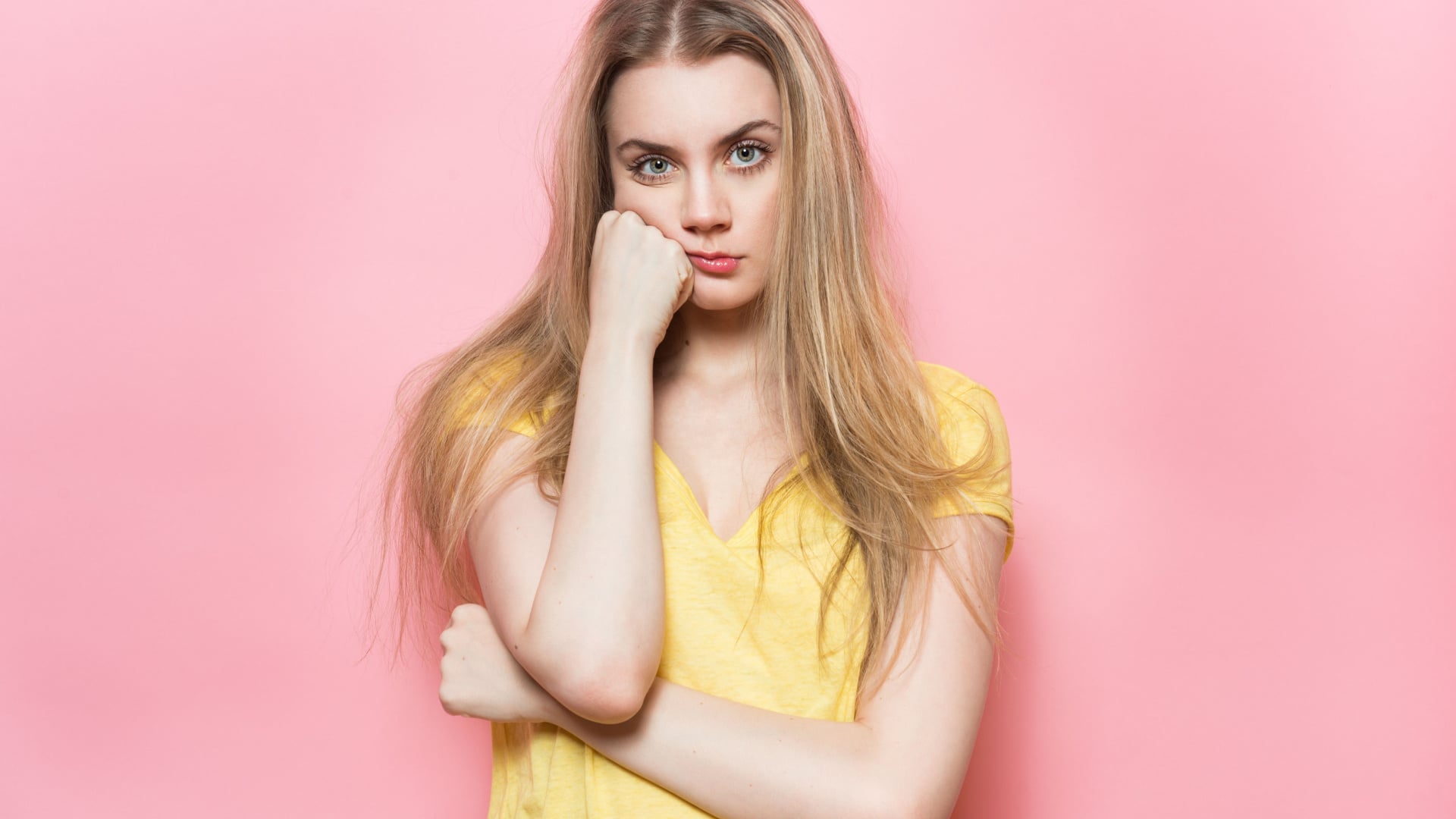 woman with her hand on her face who looks very bored on a pink background