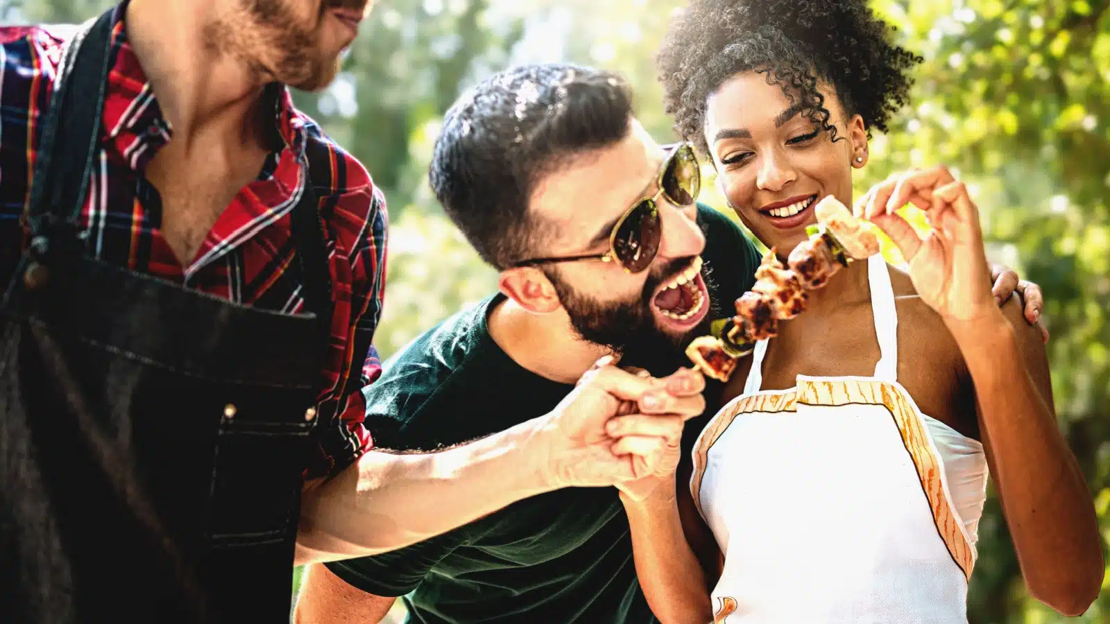 Party guests enjoying a delicious kabob at a BBQ.