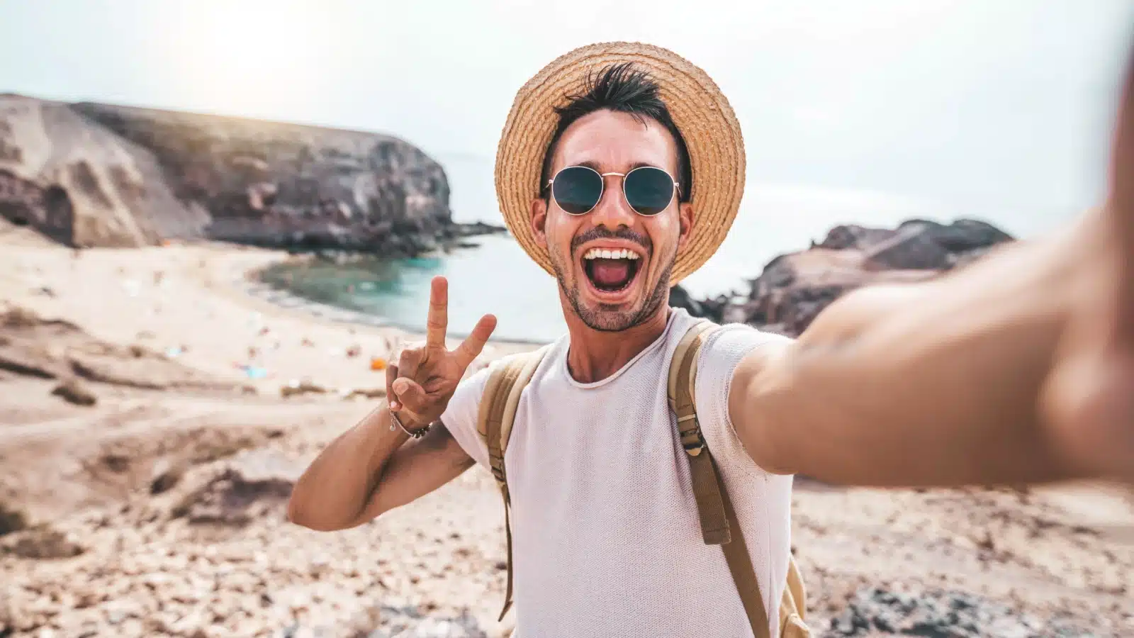 A happy tourist taking a selfie at a quiet beach to represent the best secret travel hacks.