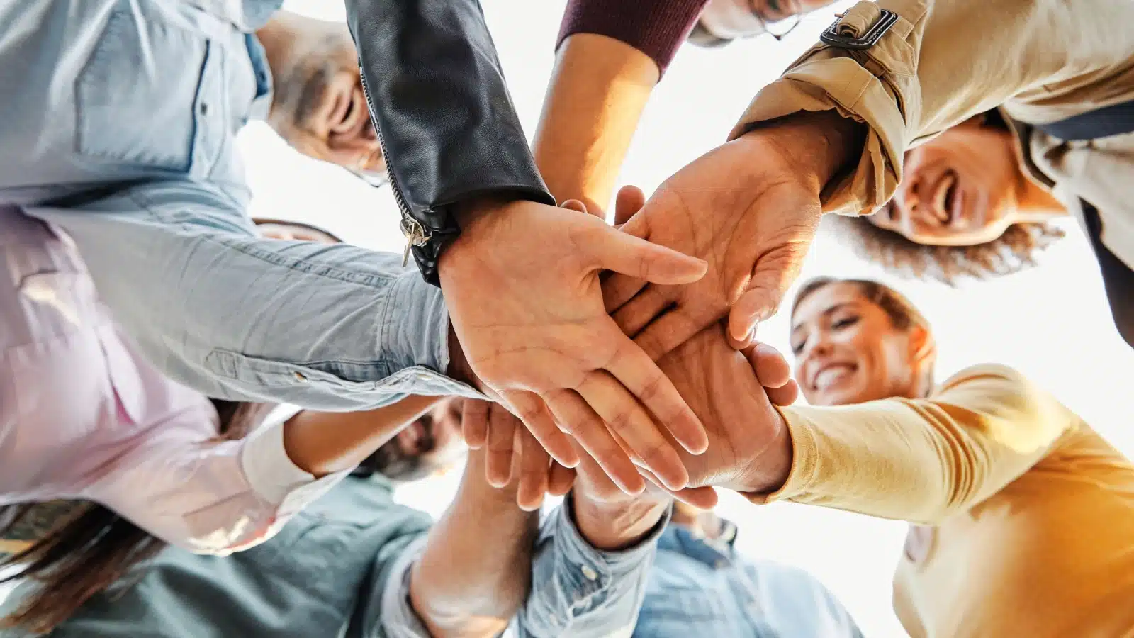 A group of people with their hands together, showcasing that together, we have the power.