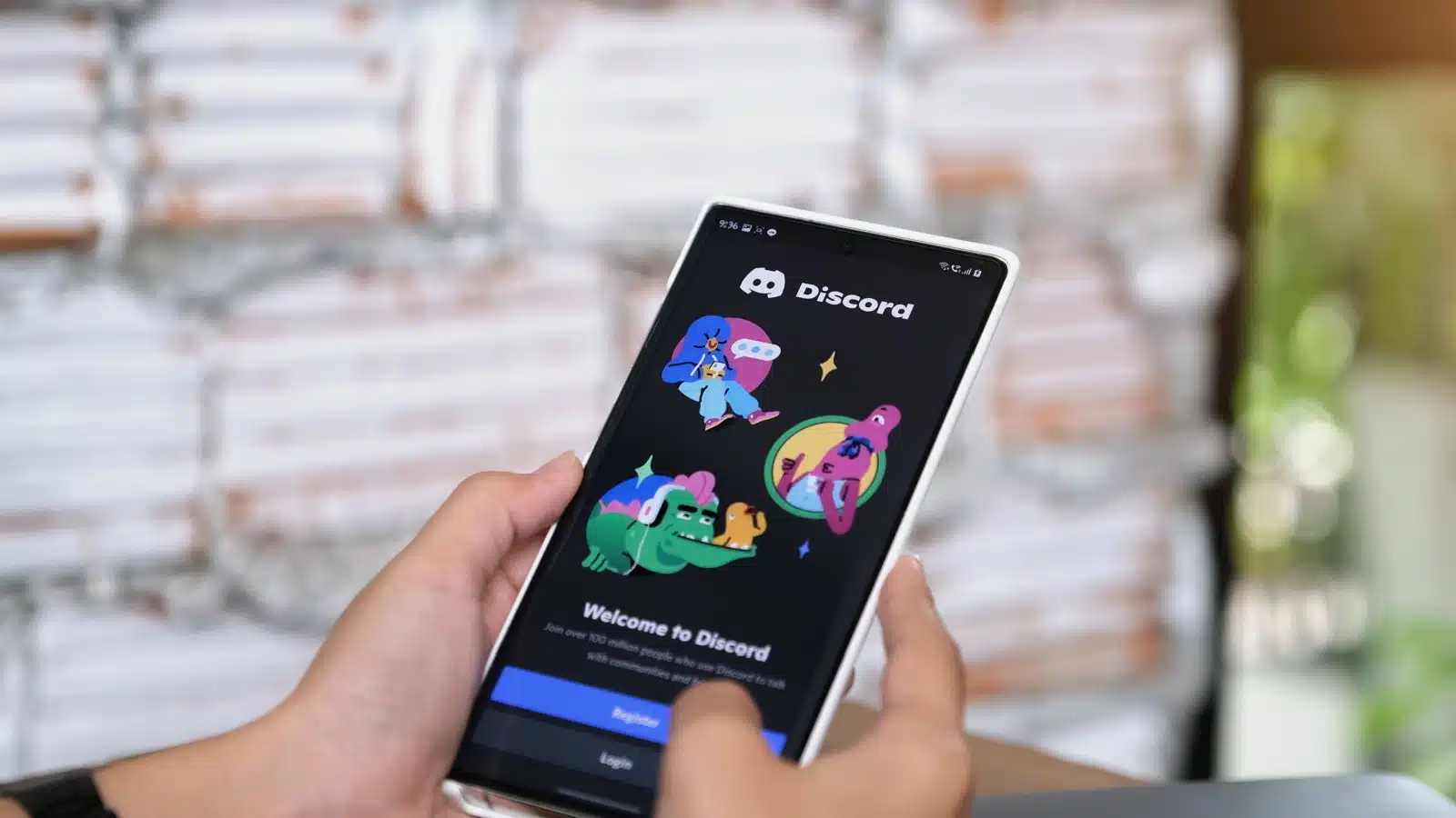 A person holding their cell phone with the Discord app welcome screen on it.