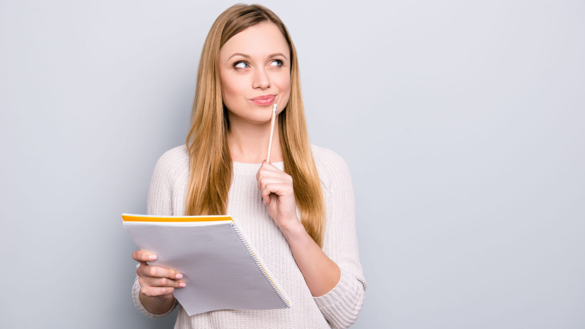 woman holding a notbook and a pencil, thinking