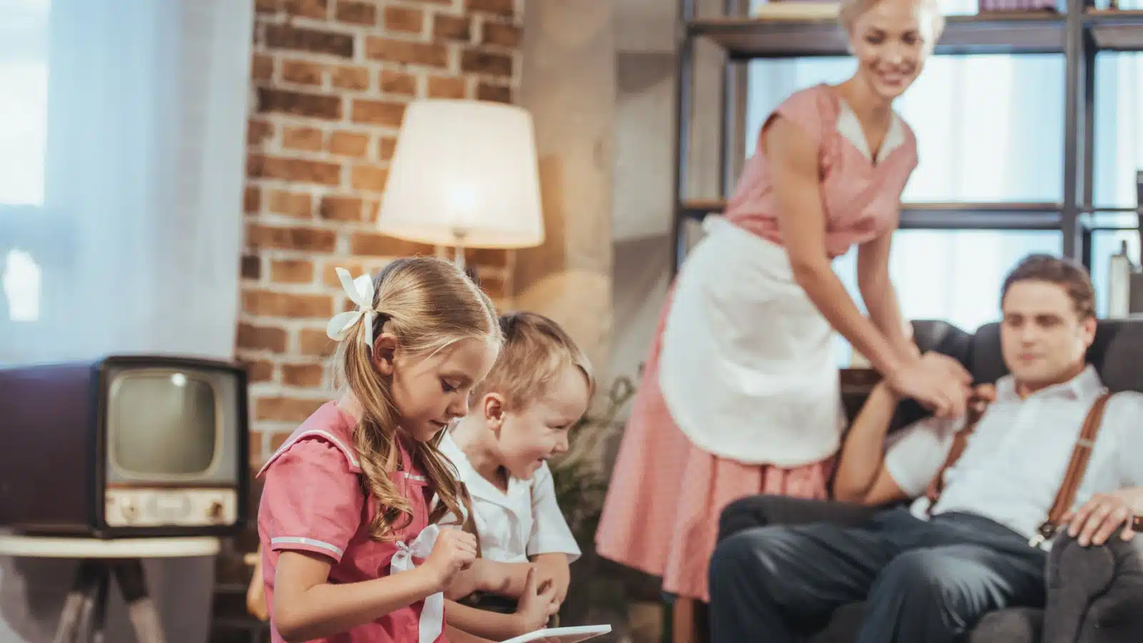 A 1950s family. Kids play in foreground, while a housewife dotes on her husband who's relaxing in a chair in the background.
