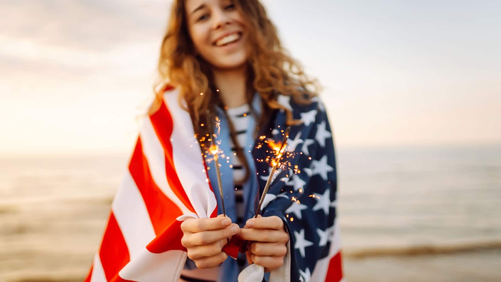 A girl draped in an American flag holds sparklers to represent American culture shock.