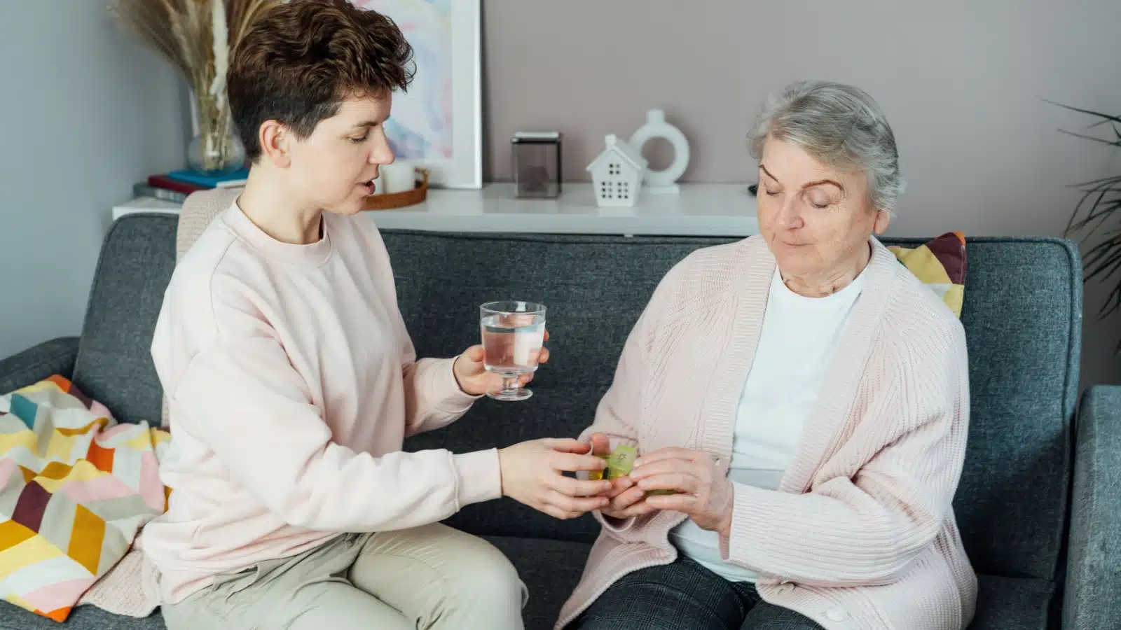 An adult daughter helps her elderly mom with her medicine.