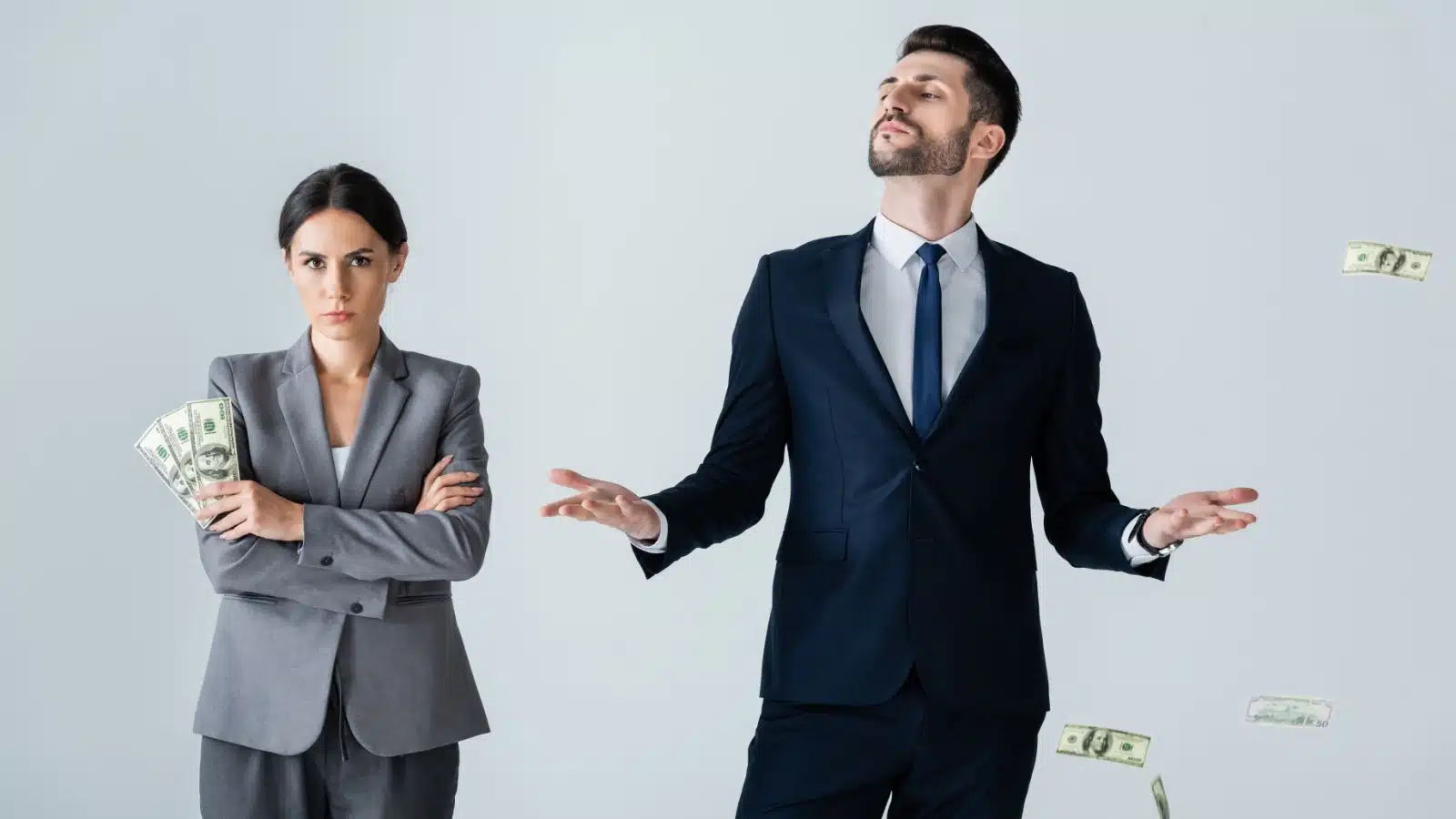 A woman crosses her arms, clutching her money, while an arrogant man watches cash float all around him to represent the difference between financial advice for men vs financial advice for women.