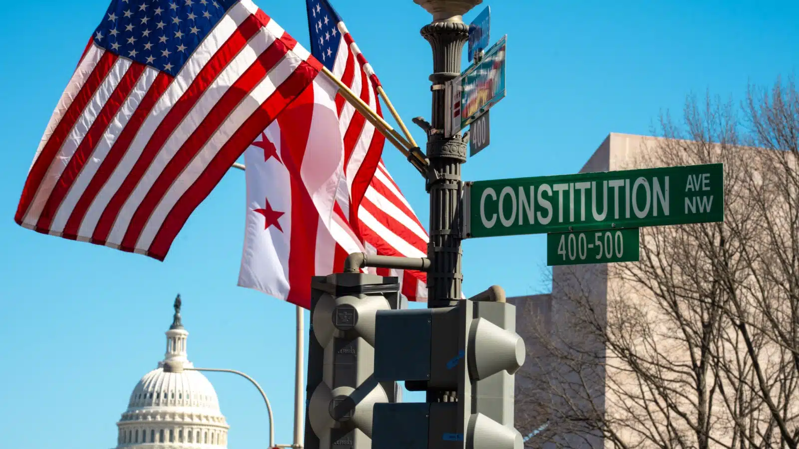 American flags waving on Constitution Avenue with the dome of the Capital Building in the background to represent good things about America and answer the question "What is good about America?"