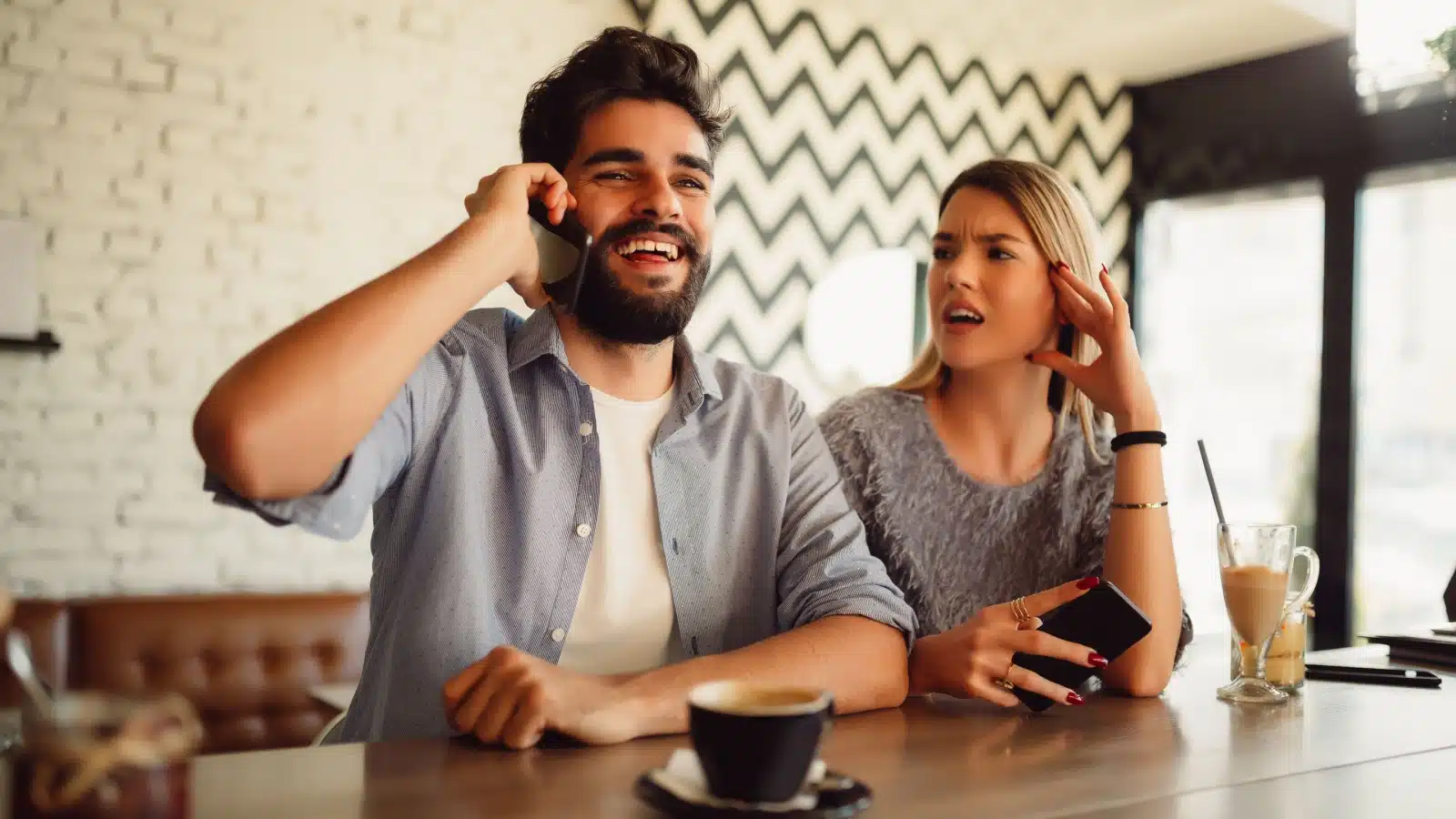 A man talks on the phone during a date, ignoring the woman who is clearly upset.
