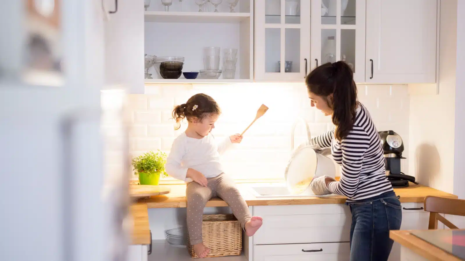 A mom prepares dinner while watching her daughter.