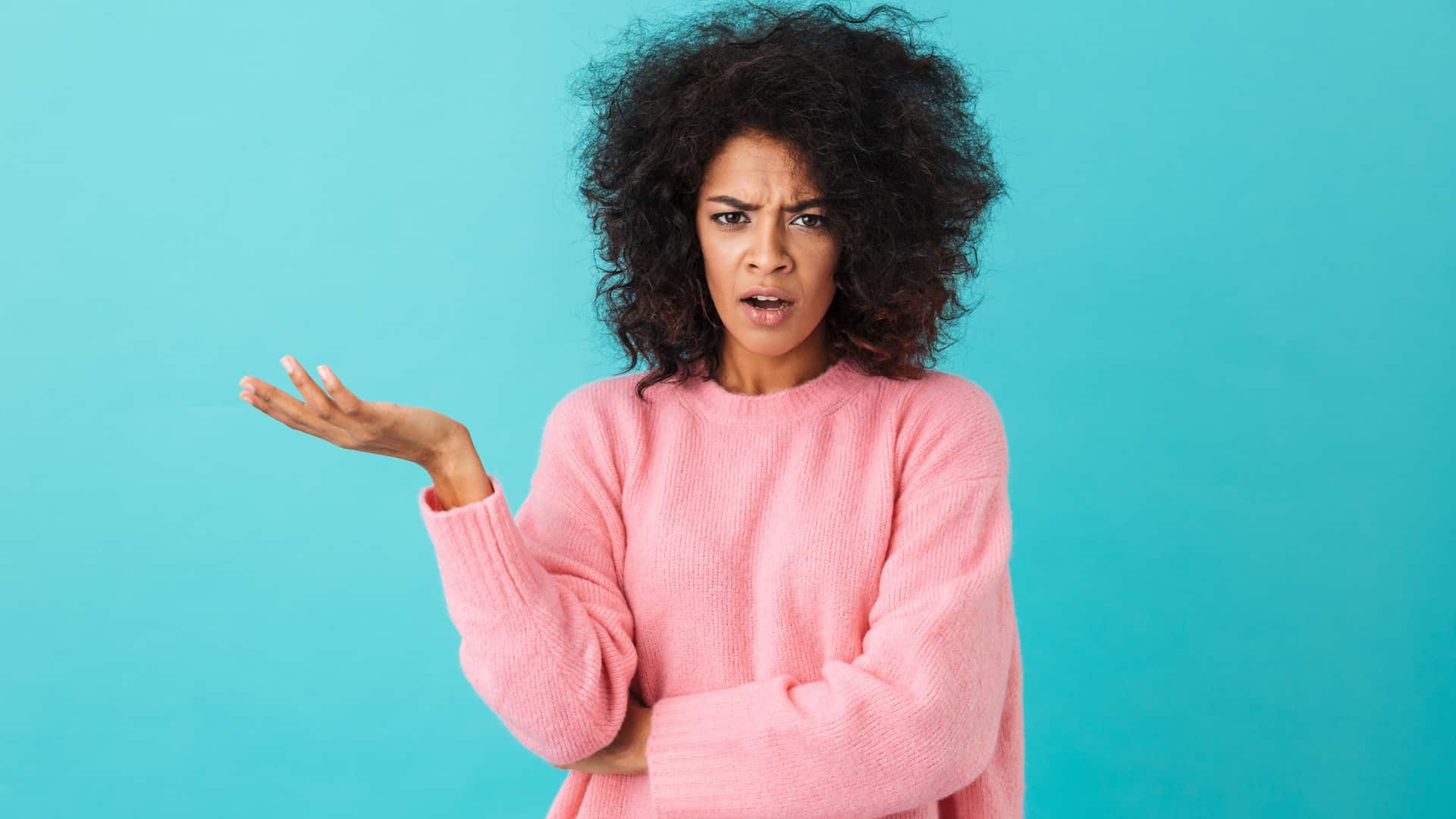 woman with mad and confused facial expression holding one hand up as if to say "what?".