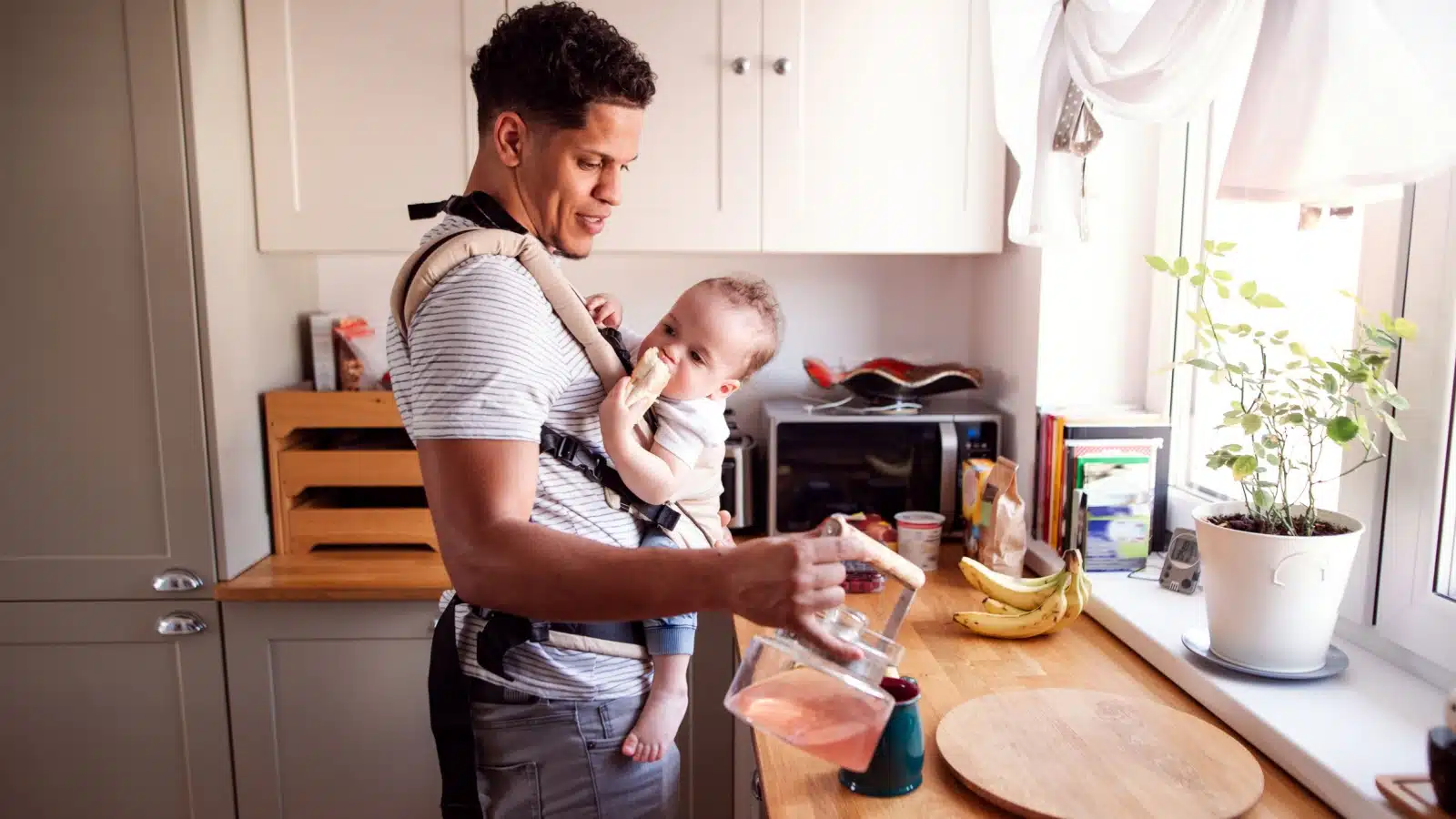 A stay at home dad takes care of his baby in the kitchen.