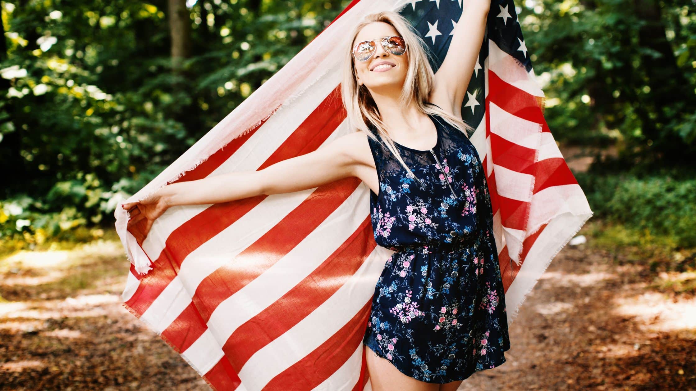 Woman holding the American flag behind her bag like a cape