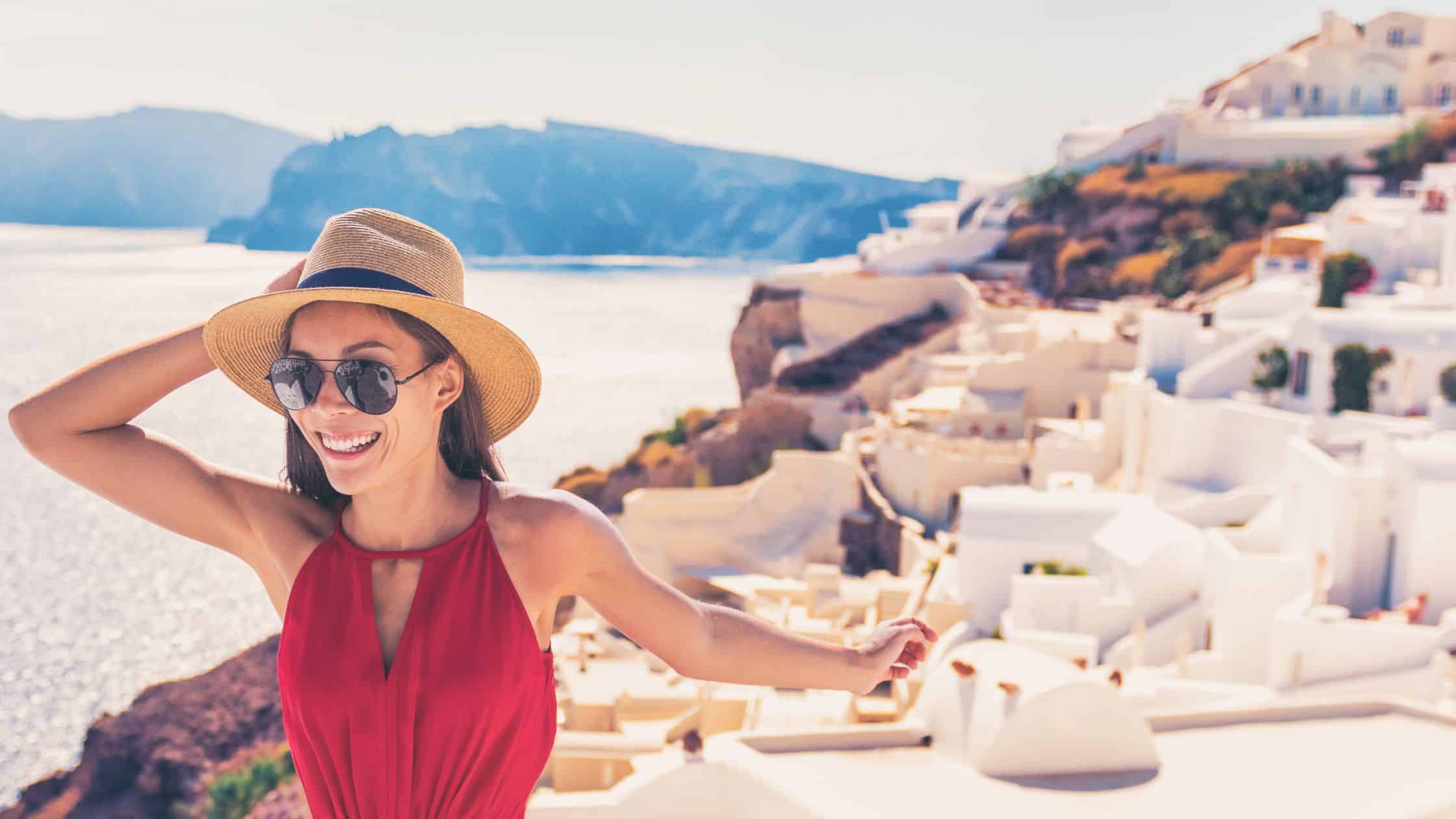 Woman wearing red smiling with Santorini in the background