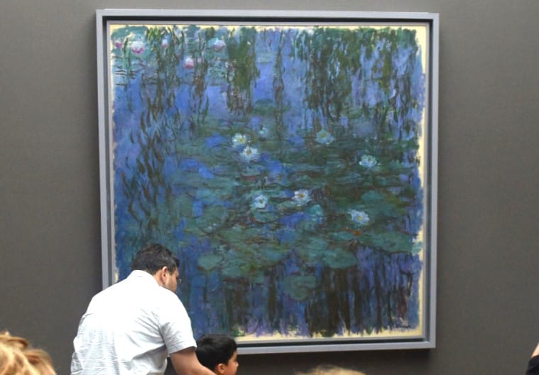 A father and son observe Claude Monet's Blue Water Lillies at Museum d'Orsay in Paris