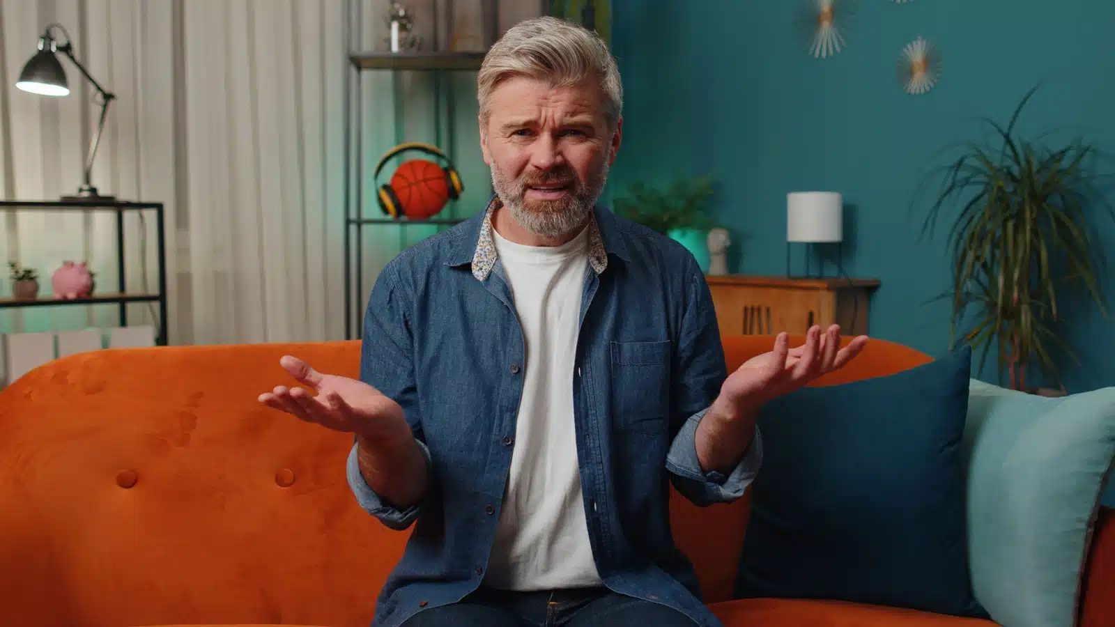 An annoyed looking middle aged man sitting on his couch to represent the things we loved as kids but hate as adults.