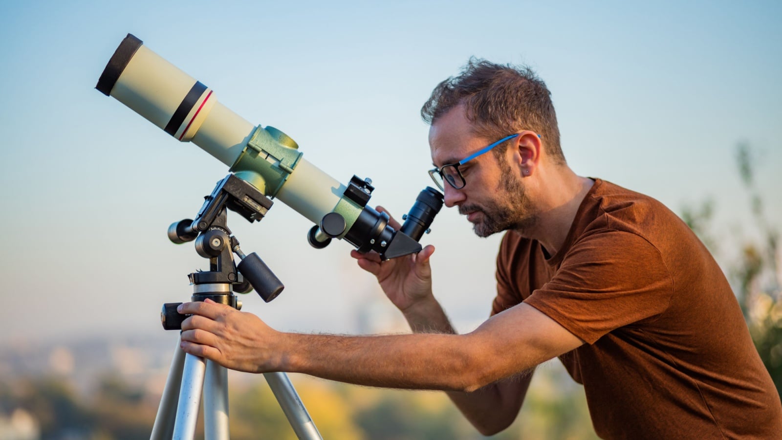 An hobby astronomer sets up his telescope outside.