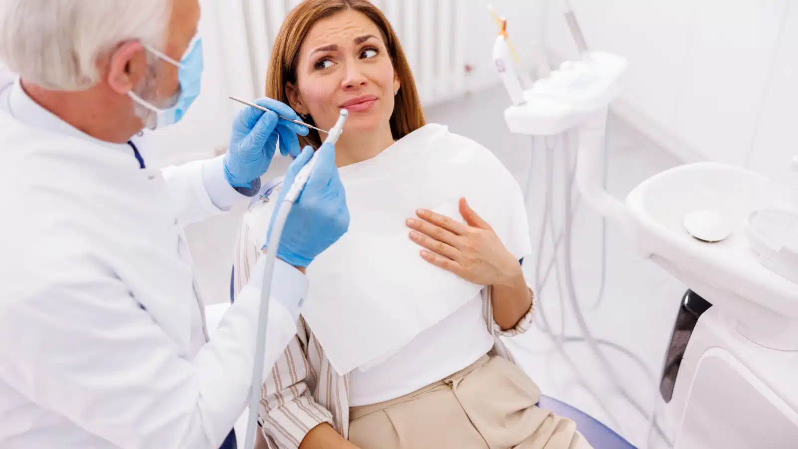 A nervous woman sits in a dentist chair.