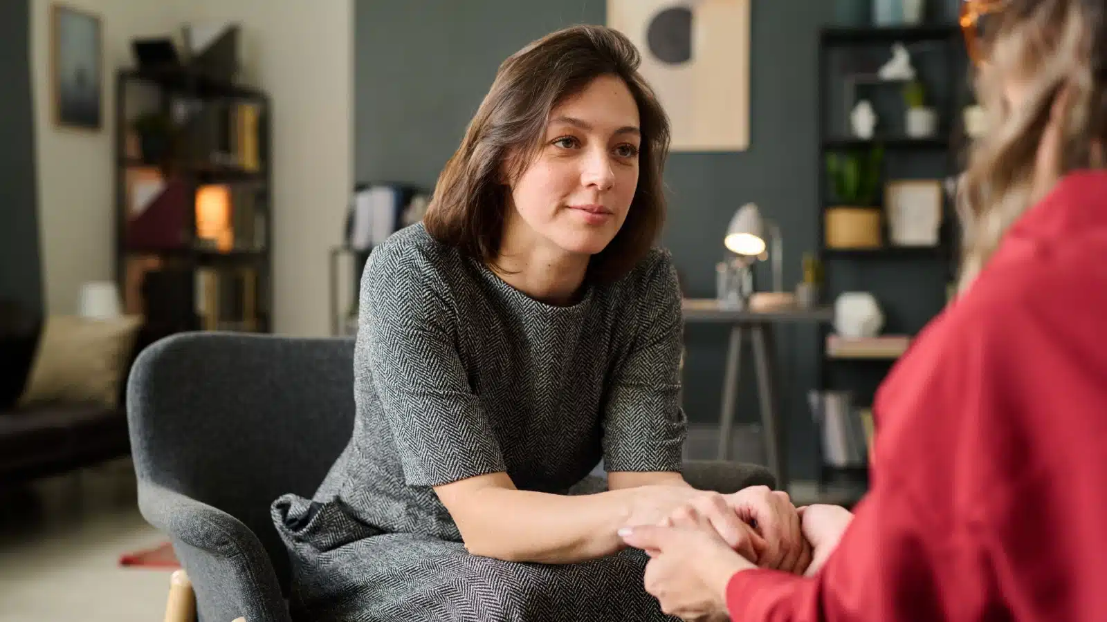 A therapist holding her clients hands, showing empathy.