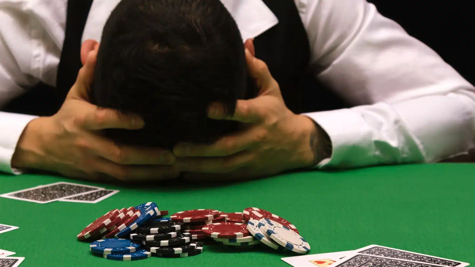 A devastated man lays his head on the poker table after losing big.
