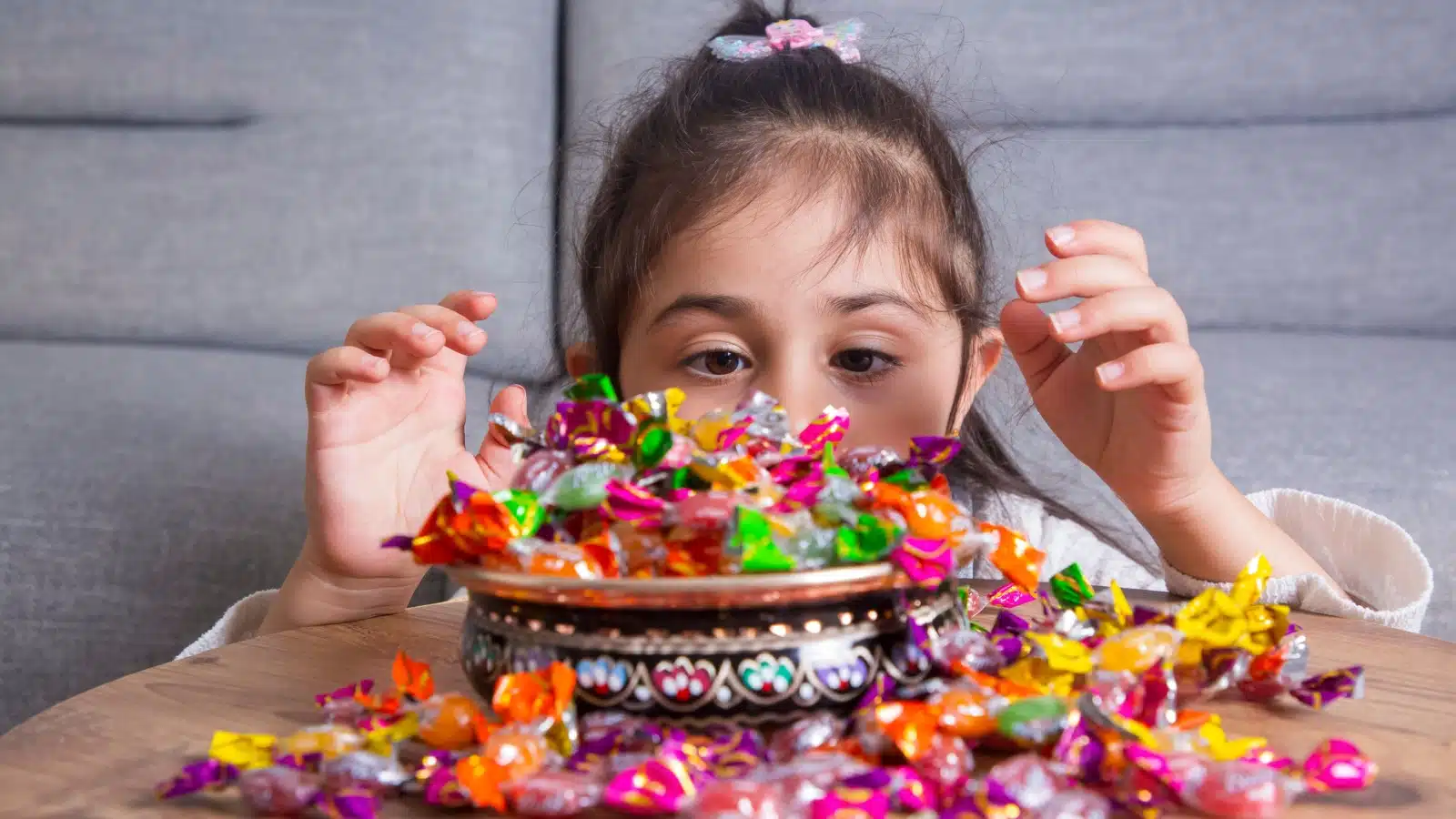 A little girl gets ready to dive into a big bowl of candy.