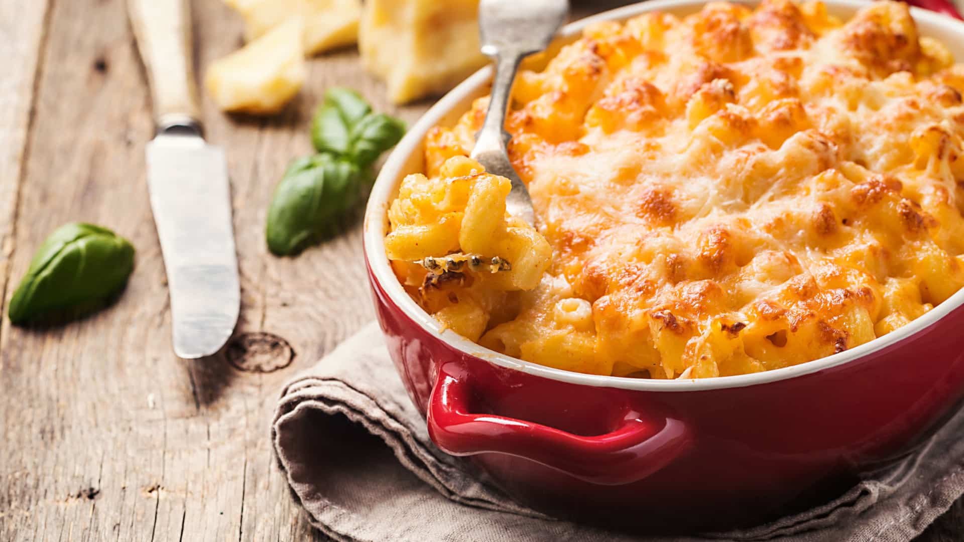 gourmet mac and cheese in a red pot with a fork lifting some noodles out