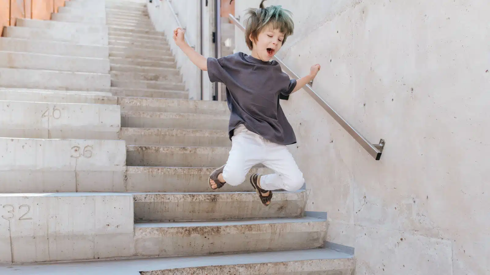 A happy kid jumps down the stairs.