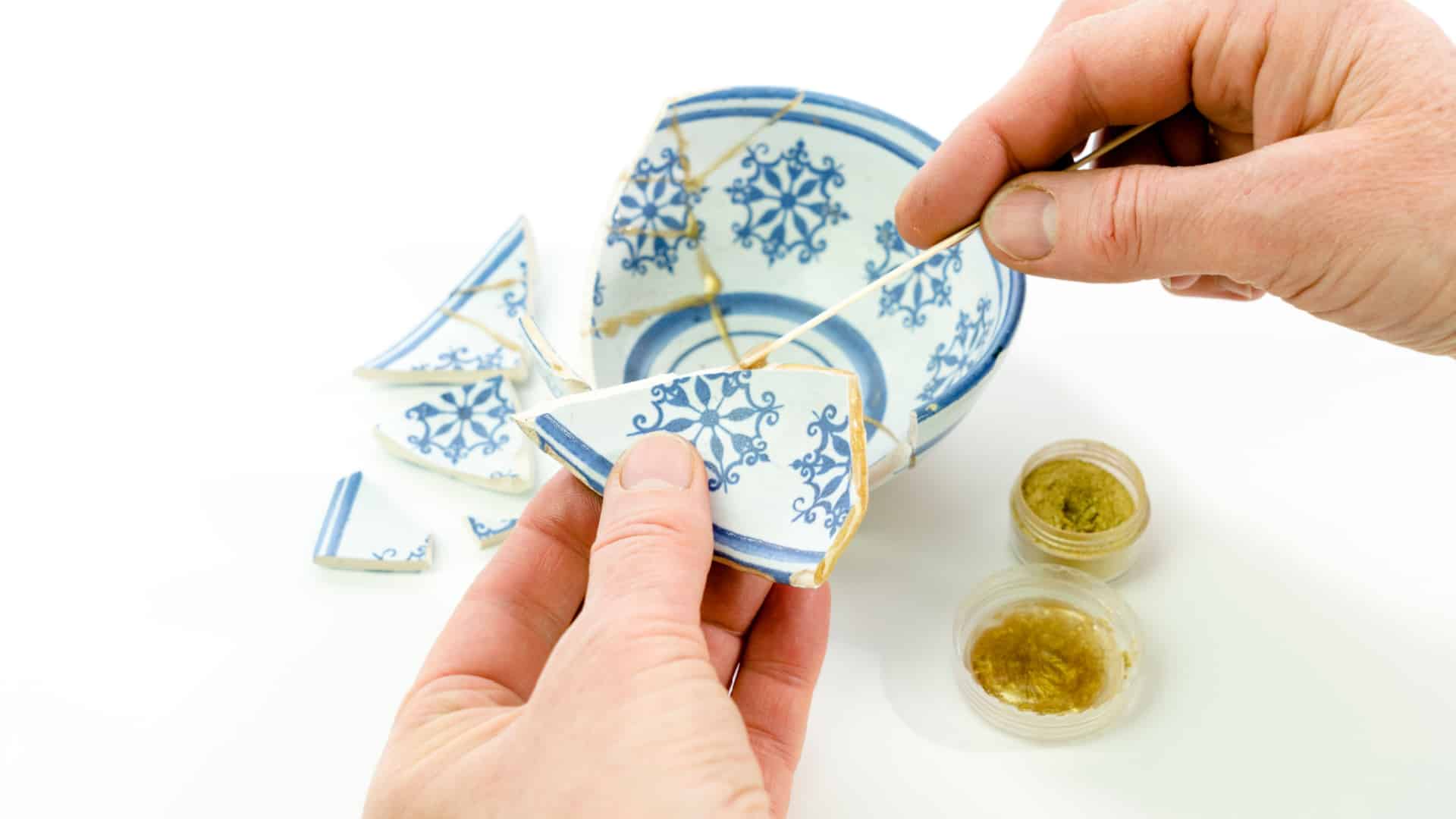 hands fixing a tiny bowl with kintsugi