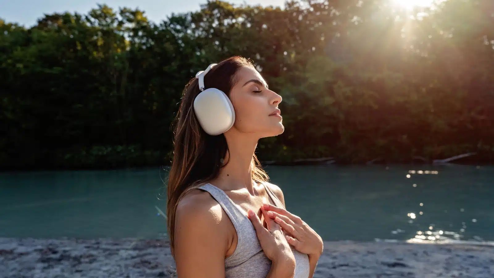 A woman practices mindfulness while outside wearing headphones.