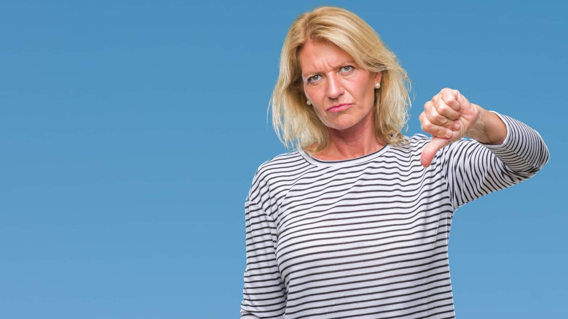 older woman with facial expression showing dislike and giving a thumbs down sign