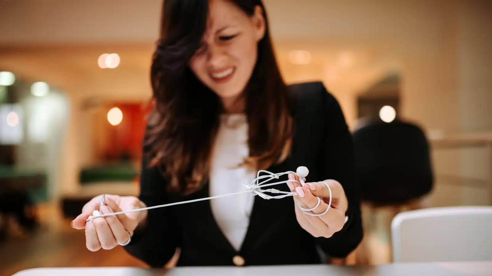 A stressed woman stares at her tangled headphone wires.