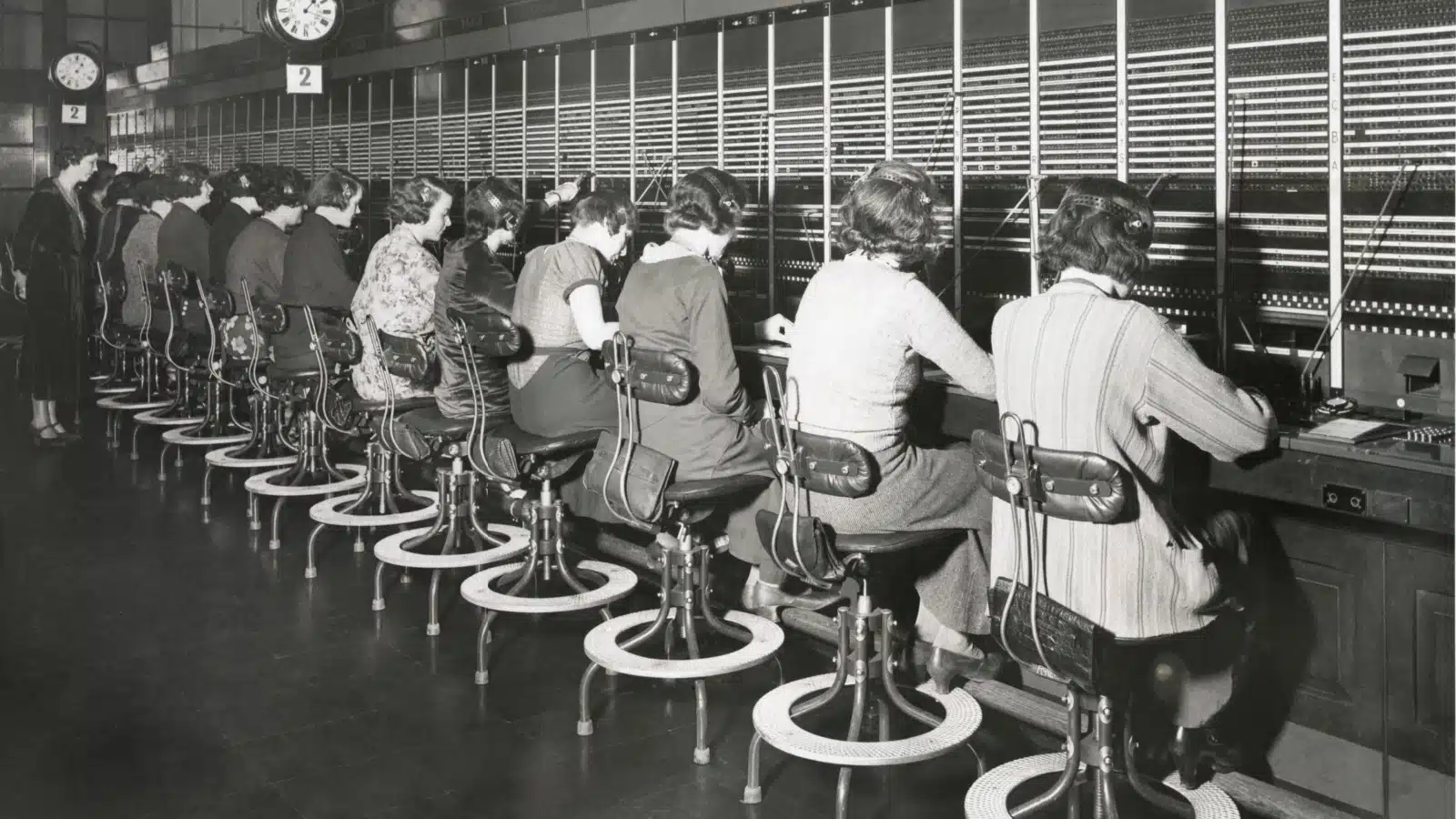 Historical photo of women working as telephone operators. They're using switchboards to connect calls.