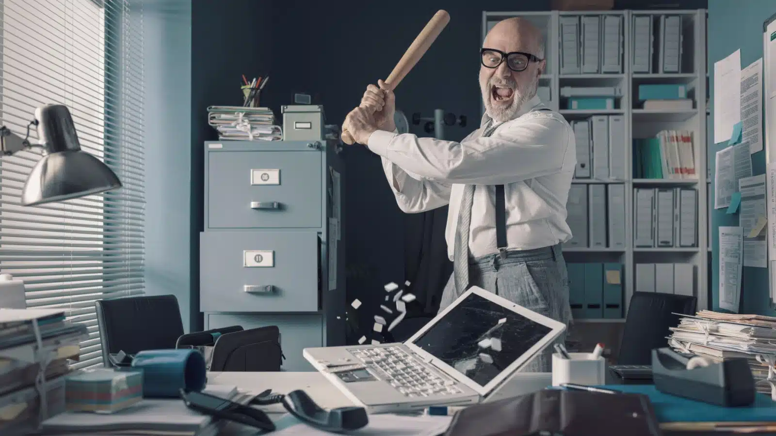 A stressed out worker takes a baseball bat to his computer to represent the question "Why do minor inconveniences make me so angry?"