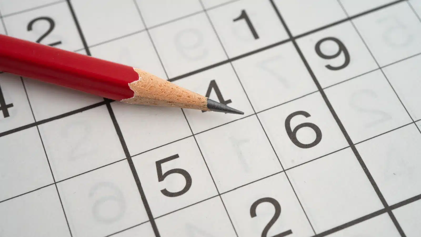 A pencil lays on top of a Sudoku puzzle.