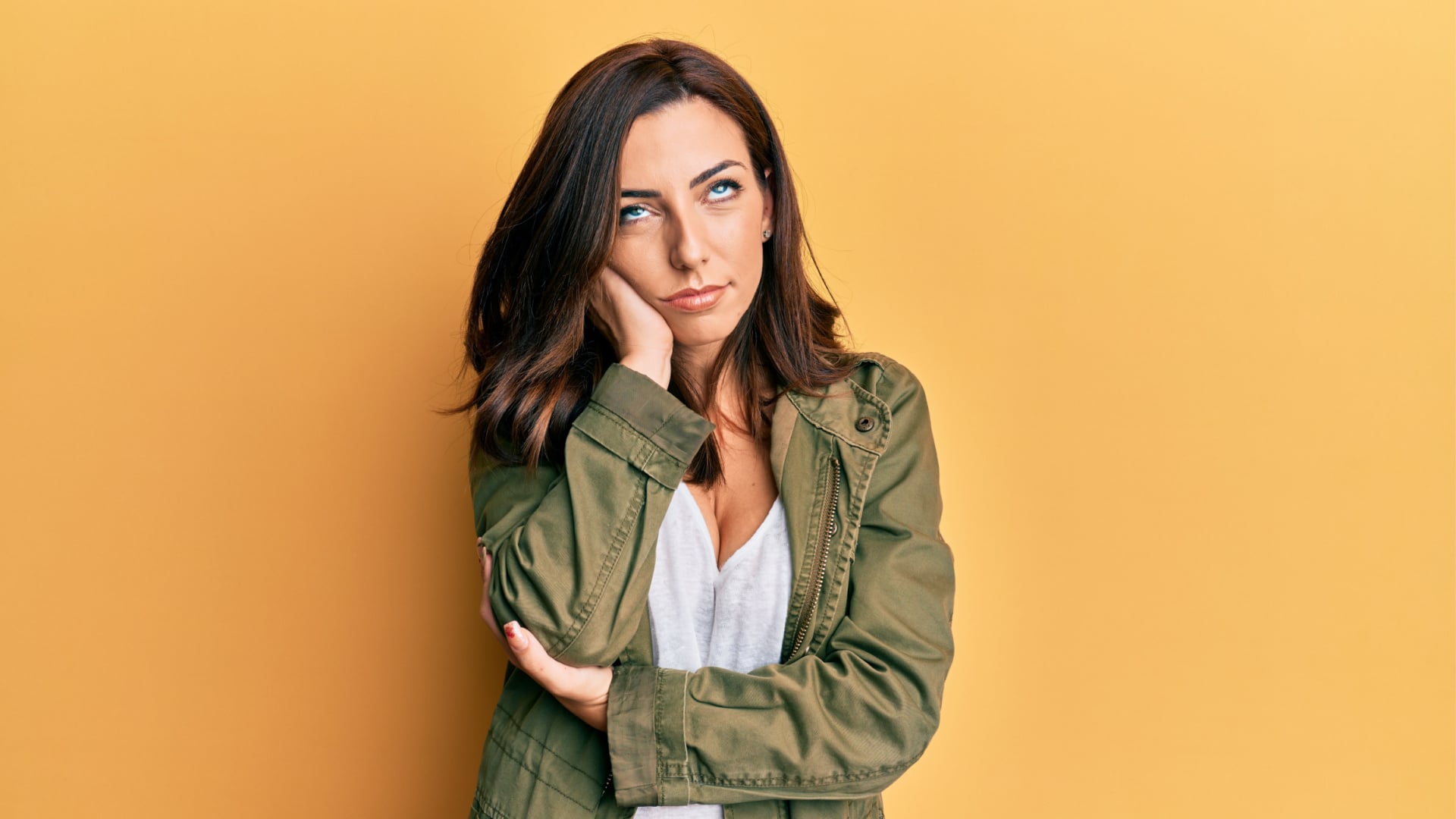 Pretty woman with an annoyed and bored look on her face on an orange background.