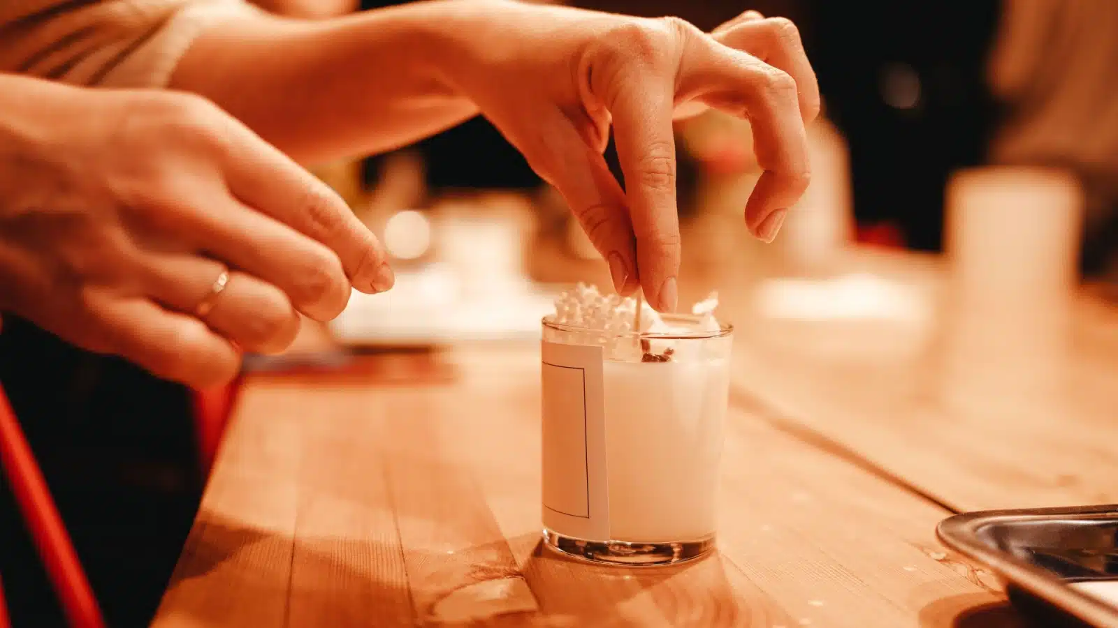 Hands putting the finishing touches on a homemade candle.