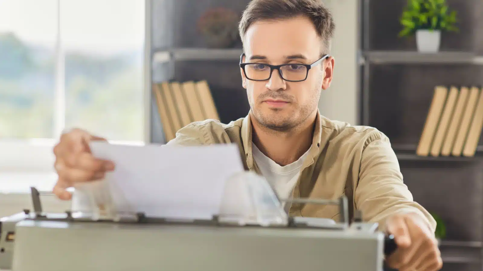 A man doesn't look happy as he pulls his first page from the typewriter.