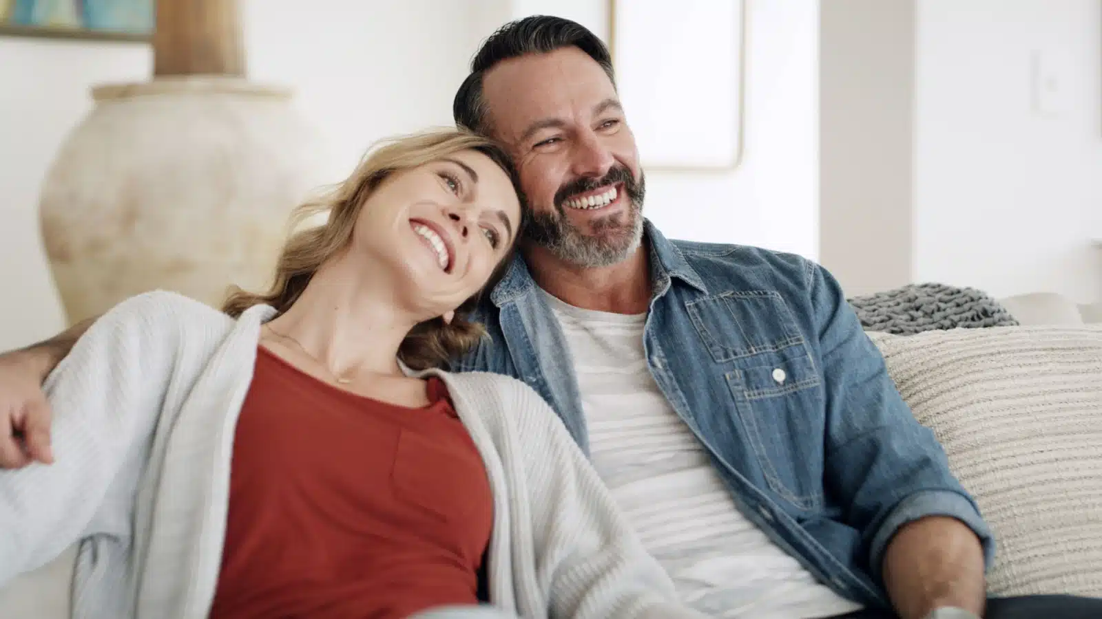 A happy couple rests on the couch together.