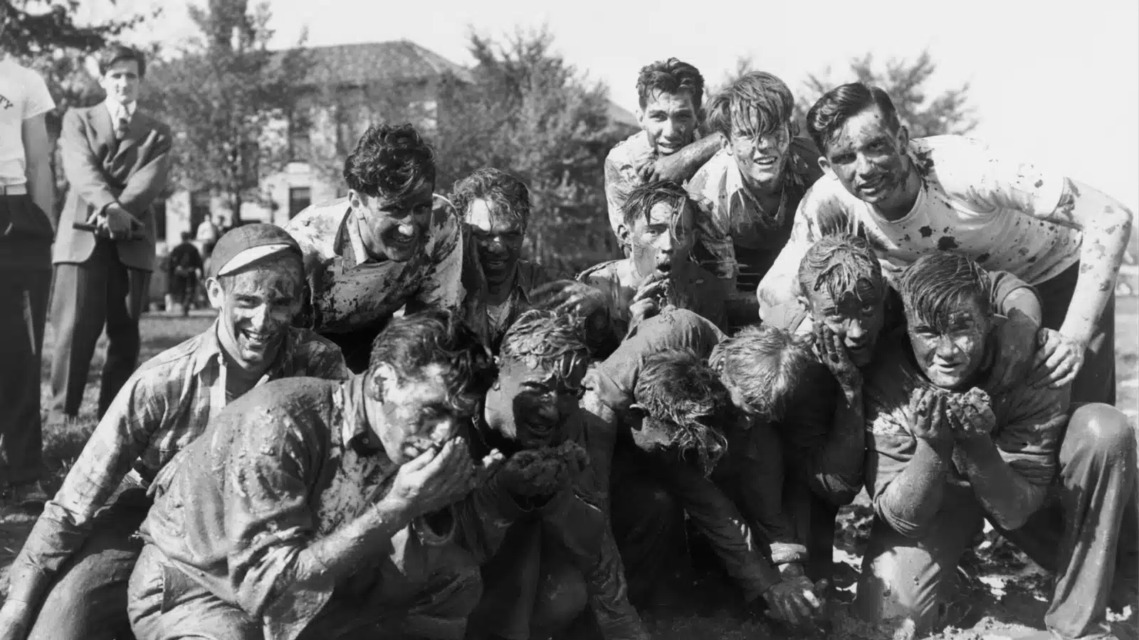 This historic photo shows a fraternity initiation ritual where recruits are forced to eat mud as a form of hazing.