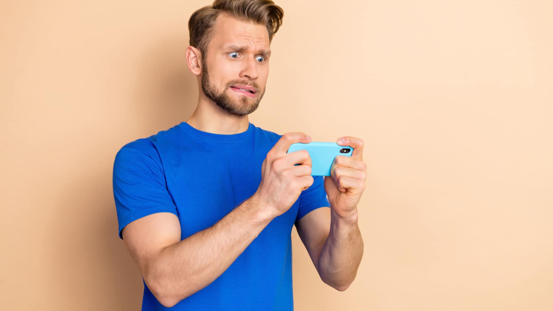 Man holding phone looking like he's concentrating hard.