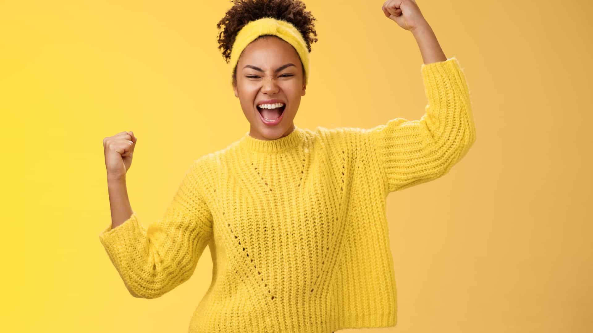 happy woman dressed in yellow celebrating her accomplishments on a yellow background