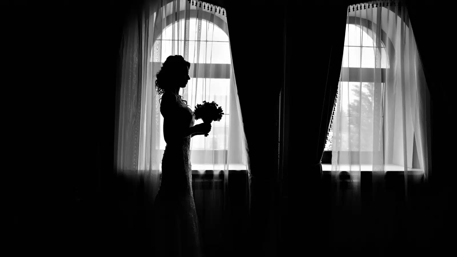 Black and white shadowy image of a bride getting ready for a wedding.