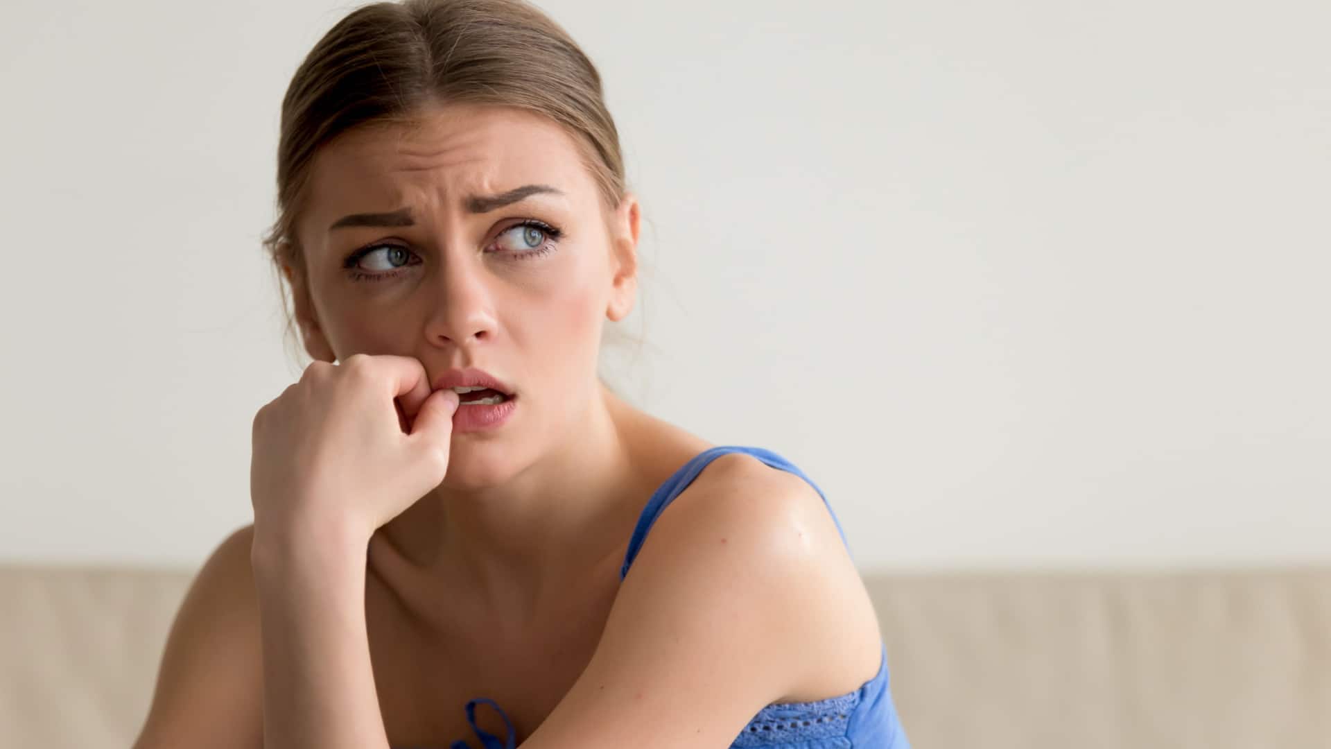 sad woman sitting with her hand at her mouth.