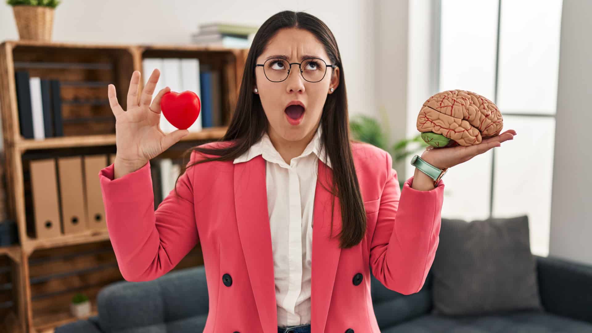 therapist holding up a brain and a heart, making a funny face