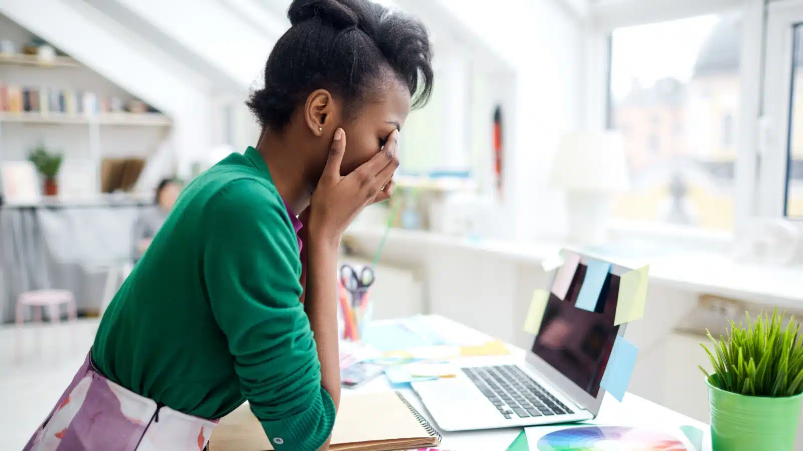 An overwhelmed worker struggles to turn on her laptop.