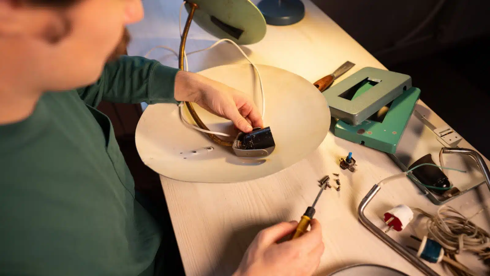 A man tinkers with a broken lamp.