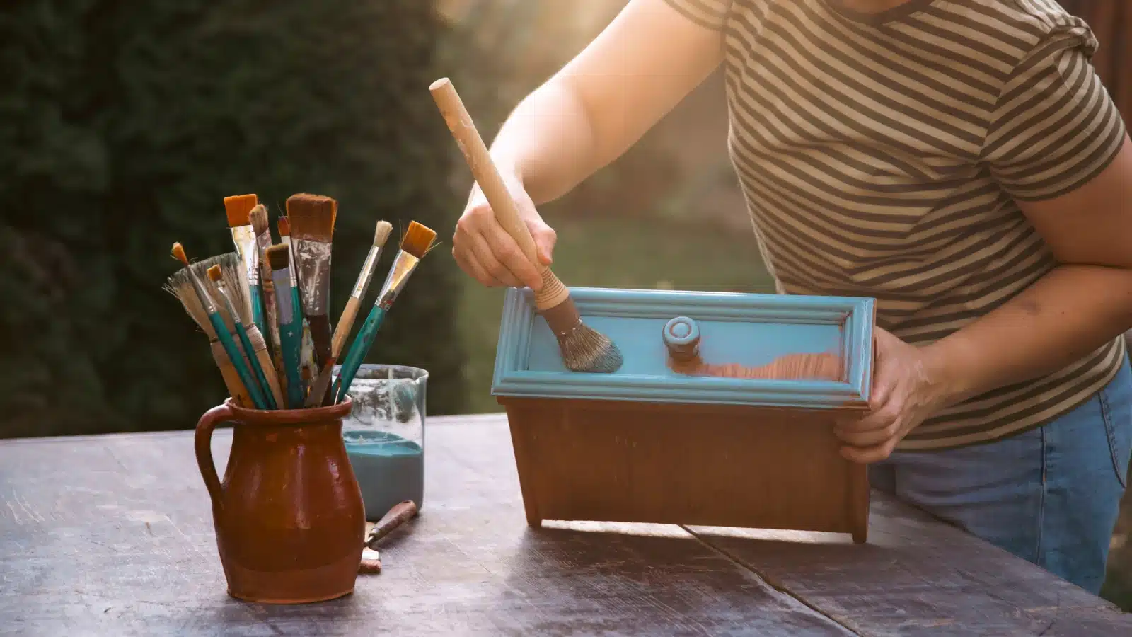 A woman upcycles a drawer by giving it fresh paint.