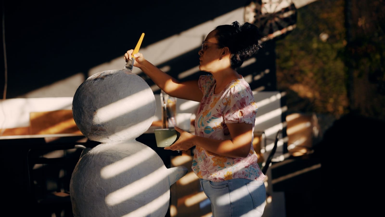 A woman paints her papier mache project.